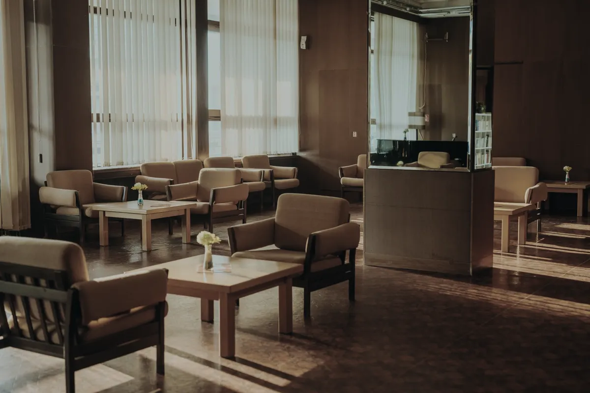 The picture shows a quiet common room with empty chairs and daylight, and no people.